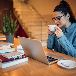 Focused woman working on a laptop with coffee, representing daily energy and productivity support.