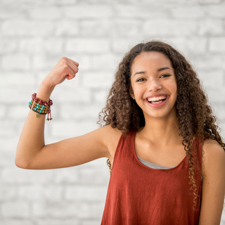 Smiling woman flexing arm strength, symbolizing strong bones and mobility from calcium and vitamins D & K.