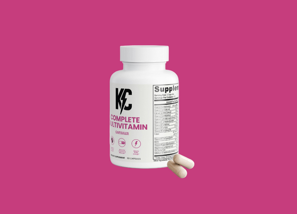 White bottle of KC Complete Multivitamin with two capsules placed in front.