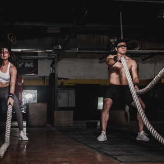 Two people using battle ropes in a gym, showing power, energy, and endurance during high-intensity training.