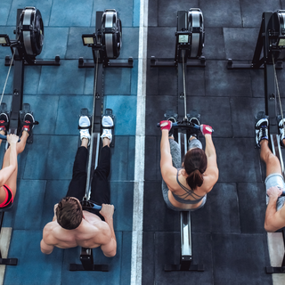 Group of athletes on rowing machines in a gym, representing strength, endurance, and explosive workout power.