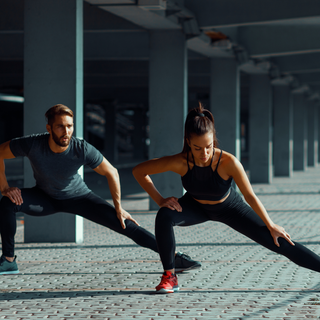 Two athletes stretching outdoors, emphasizing flexibility, mobility, and faster post-workout recovery.
